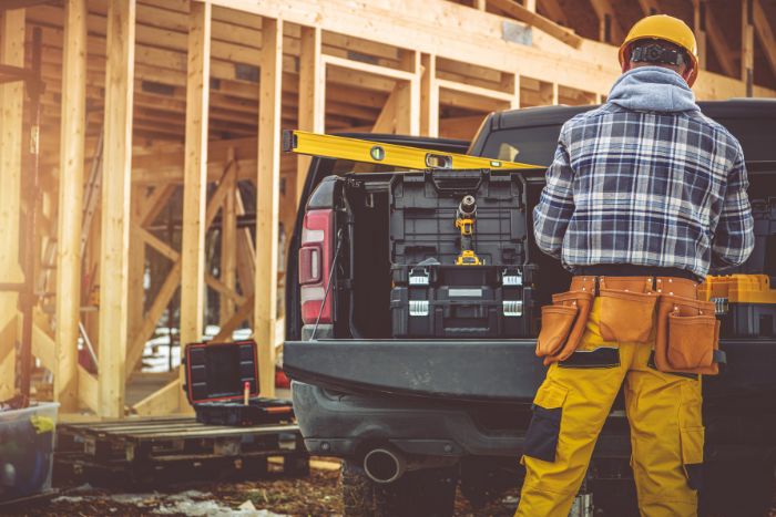 A construction worker standing beside a work truck at a building site.