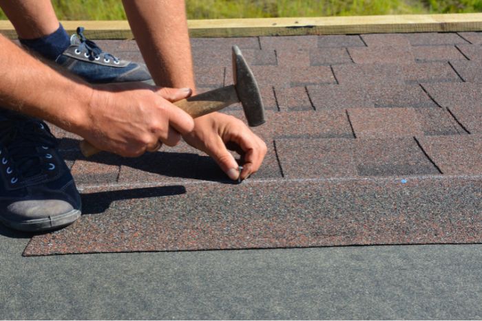 A roofer installing shingles on a house.